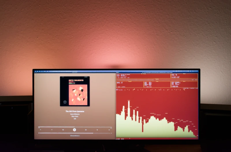 Ultraširoký monitor s Music Assistantem a zeleným frekvenčním vizualizérem s okolním osvětlením